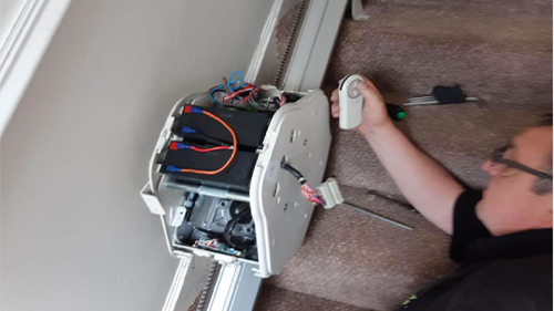 Technician fitting and testing a curved stairlift system during home installation process